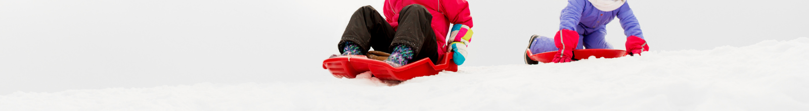 Kids on toboggans going down a snow hill