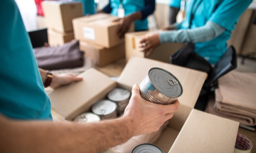 People helping put canned food in boxes