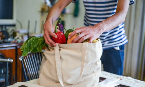 Someone unloading produce from a shopping bag