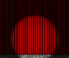 A red curtain on a stage with a spotlight on it 