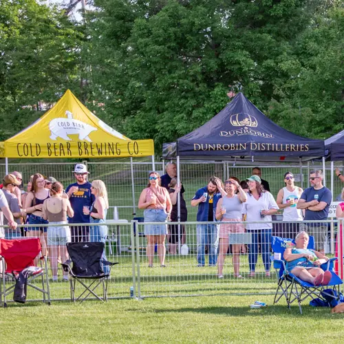 A group of people in a fenced area enjoying a beverage 